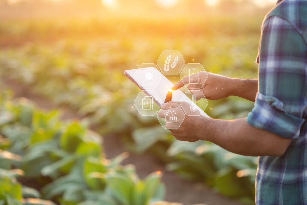 Picture of a person in a field holding an iPad with tech icons popping out from the iPad to symbolize tech.nology
